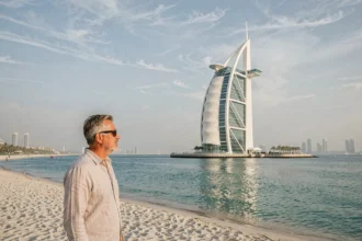 Vue extérieure du Burdž Al Arab depuis la plage de Jumeirah à Dubaï avec un homme contemplant l'hôtel en forme de voile