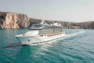 Paquebot de croisière naviguant sur la mer Méditerranée turquoise longeant une côte calcaire spectaculaire
