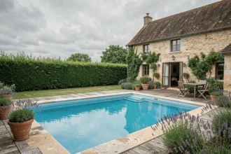 Vue d'ensemble d'un gîte avec piscine privée dans les Hauts-de-France, entouré de verdure et d'architecture rurale en pierre